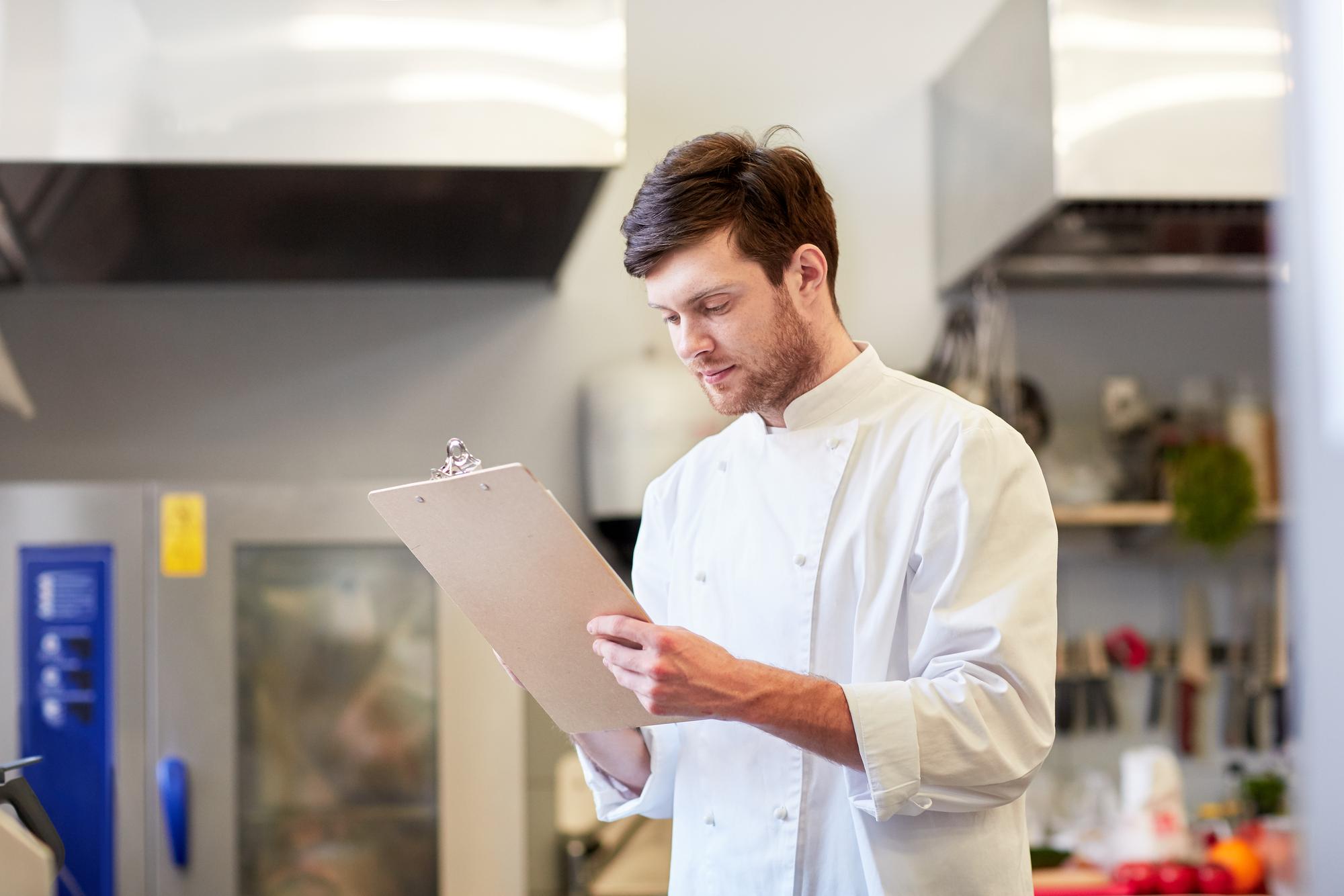 operations manager with clipboard in a kitchen